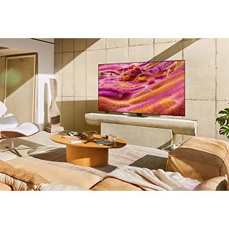 Bir Neo QLED TV, güneşli bir odada bir standa yerleştirilmiş. Ekranda rengarenk soyut bir manzara gösteriliyor.