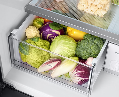 超大保鮮蔬果室裝滿了新鮮蔬菜，如高麗菜、甜椒、青花菜、花椰菜和洋蔥。大素盒門的表面上寫著 “ Crisper+ ” 字樣。
