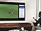  一位男士正在使用 QLED 量子電視的雙重視窗功能在同一螢幕上同時欣賞足球比賽和查看新聞。