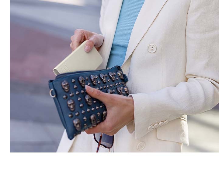 一位身著半正式米色西服的女性拿著米色閃充行動電源，邊走邊放進她時髦的手拿包中。