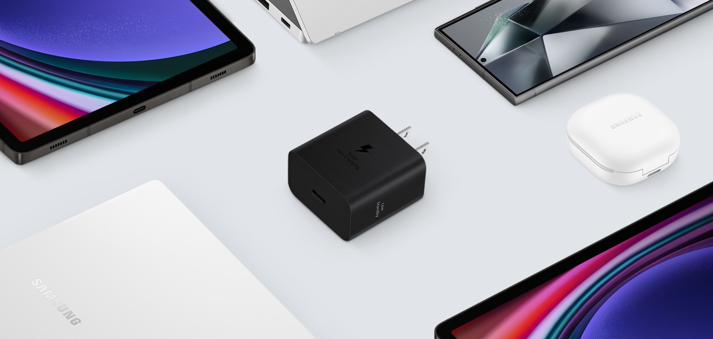 各種 Samsung Galaxy 裝置的俯視圖，中心為黑色快充旅充頭。左邊是 Galaxy Book3，右邊是白色 Galaxy Buds2 Pro、Galaxy Tab S9 和 Galaxy S24 Ultra。