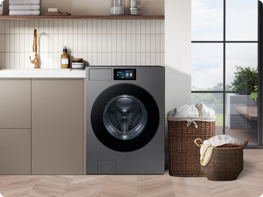 A washing machine is installed in a modern utility room, next to a sink with two full laundry baskets nearby.