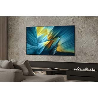 [一位男子和一隻狗在客廳中望向智慧顯示器，螢幕上呈現出一幅夢幻藍色景觀。]