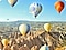 Photo taken with Wide-angle Camera shows colorful air balloons in the sky and a vast landscape in the background.