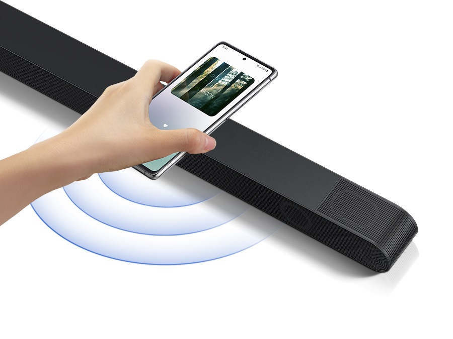 A hand taps a smartphone with the Samsung music app on-screen on the soundbar and the soundbar instantly plays music, showing how easy it is to switch from smartphone to soundbar.