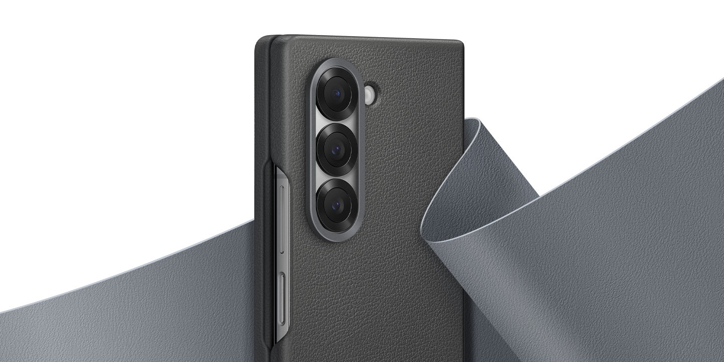 A close-up of the upper half of a Galaxy Z Fold6 in a gray Kindsuit Case. Behind the phone is a flowing swatch of soft vegan leather material that wraps itself around the back phone to showcase the premium feel of the case.