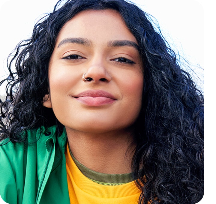 There is a portrait shot of a woman smiling, looking into the camera. Her face, hair and clothes cover most of the frame and the background is barely seen.