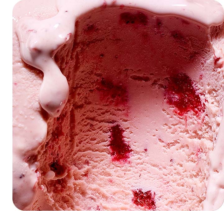 There is a detailed zoom-in shot of strawberry ice cream from the side. The details are incredibly clear with strawberry chunks inside shown and a slightly melted layer of ice cream flowing down from the top.