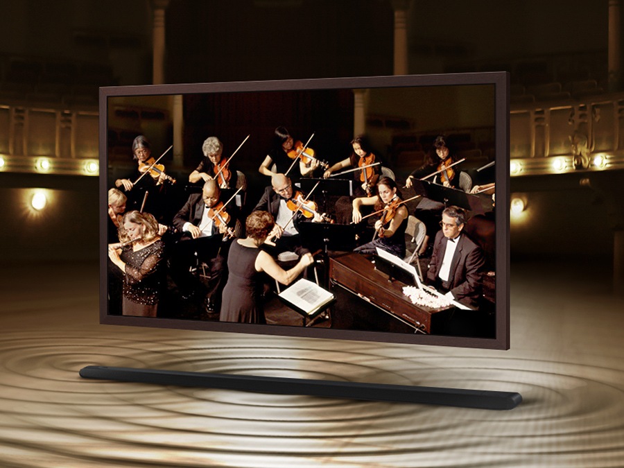 The Frame is showing an orchestra on its screen. The Soundbar is below The Frame with sound ripples coming out of it to show that the sound of the speakers on The Frame and Soundbar are perfectly synced.