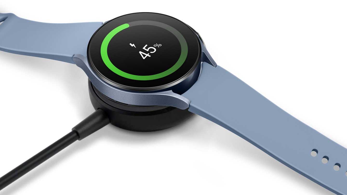 A Sapphire Galaxy Watch5 on top of a wireless charger in black showing a 45%