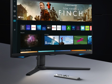 The monitor screen shows a variety of content apps and individual content choices in a card format. A remote controller rests next to the monitor.