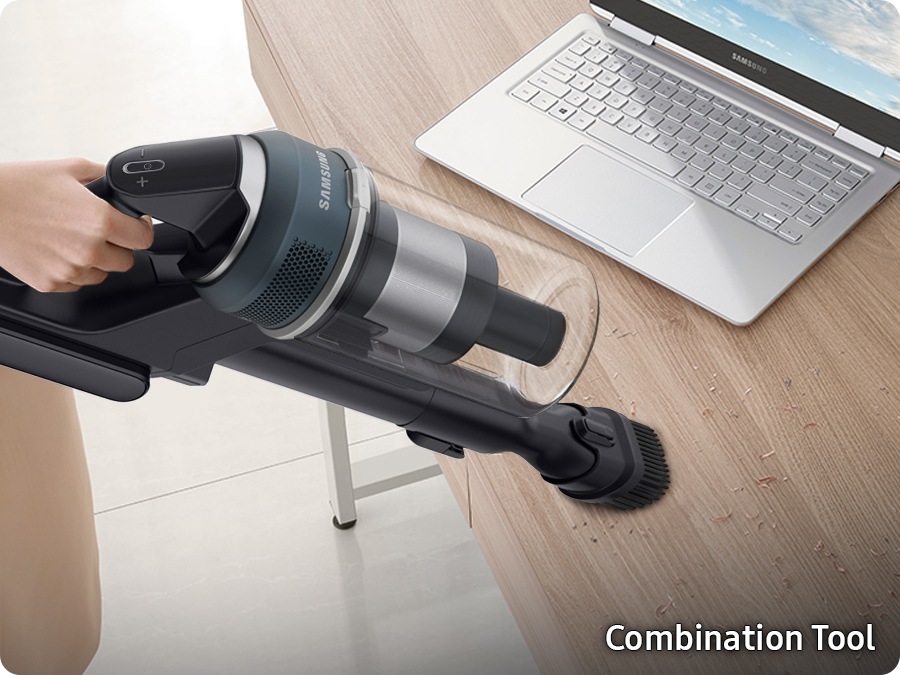 A Jet 95 with the combination tool cleans dirt on a desk near a laptop.