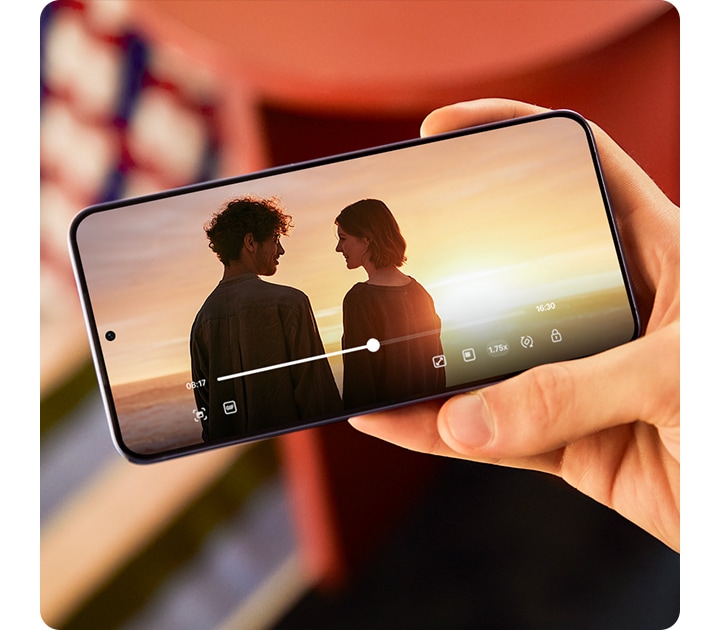 El Galaxy S24 plus se mantiene al aire libre bajo la luz del sol. En la pantalla se reproduce un vídeo con colores intensos y alto contraste.