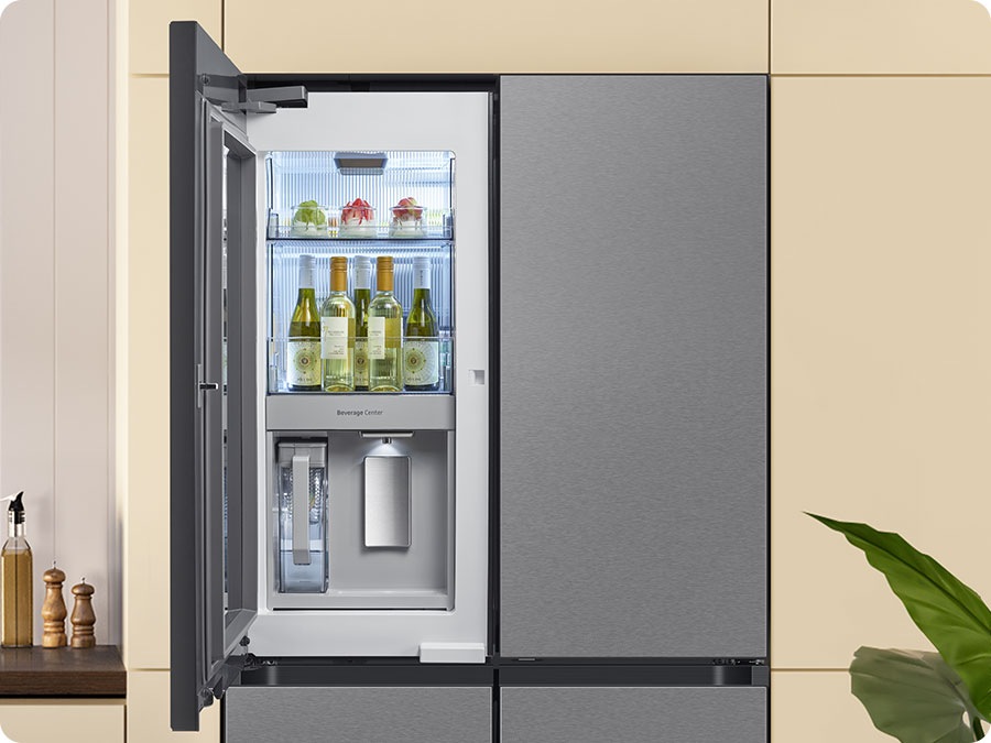 The camera zooms in to the Beverage Center inside the See-Thru Door. A hand approaches with a cup, filling it with water from the water dispenser. Next to it is an AutoFill Water Pitcher. The water is filled up.