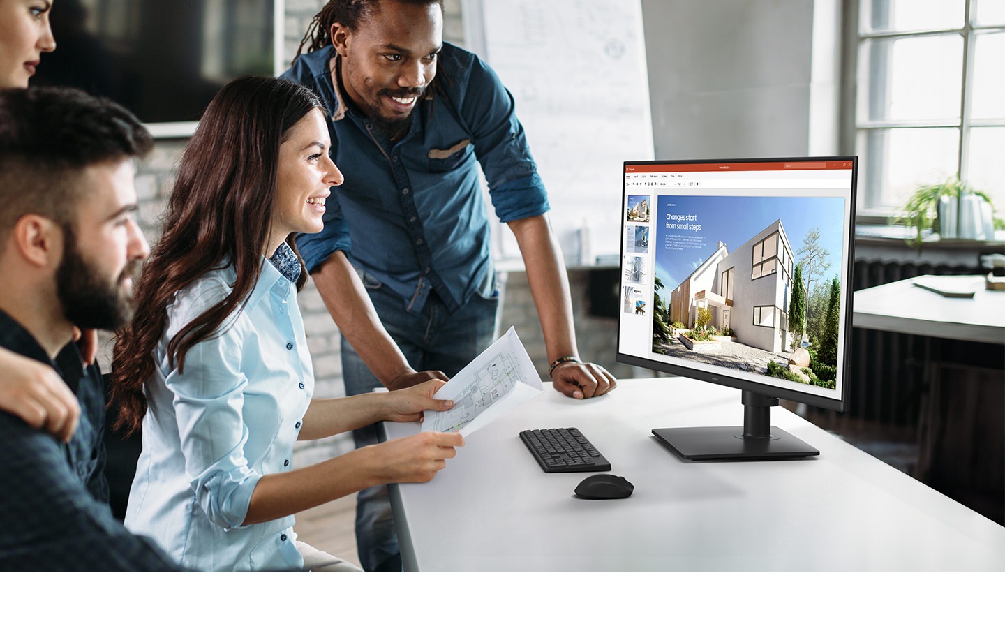 There is a group of people looking at a document on the Essential Monitor S4.