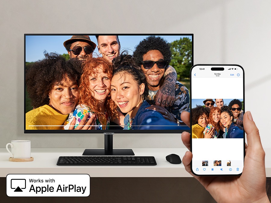 A smartphone wirelessly mirrors a group photo to a large monitor using Apple AirPlay. Works with Apple AirPlay logo.