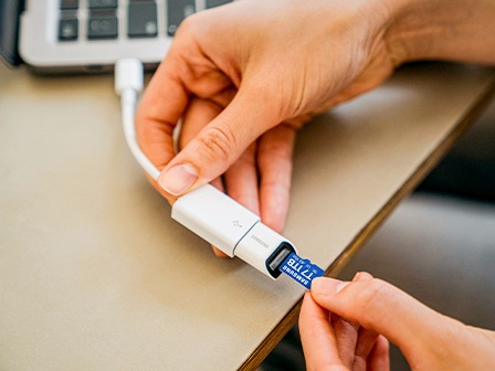 Ruka koja umeće microSD karticu T7 u spojeni adapter prijenosnog računala.