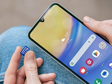 Ruka koja umeće microSD karticu T7 u pametni telefon.