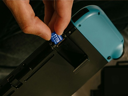 Ruka koja umeće microSD karticu T7 u ručnu igraću konzolu.
