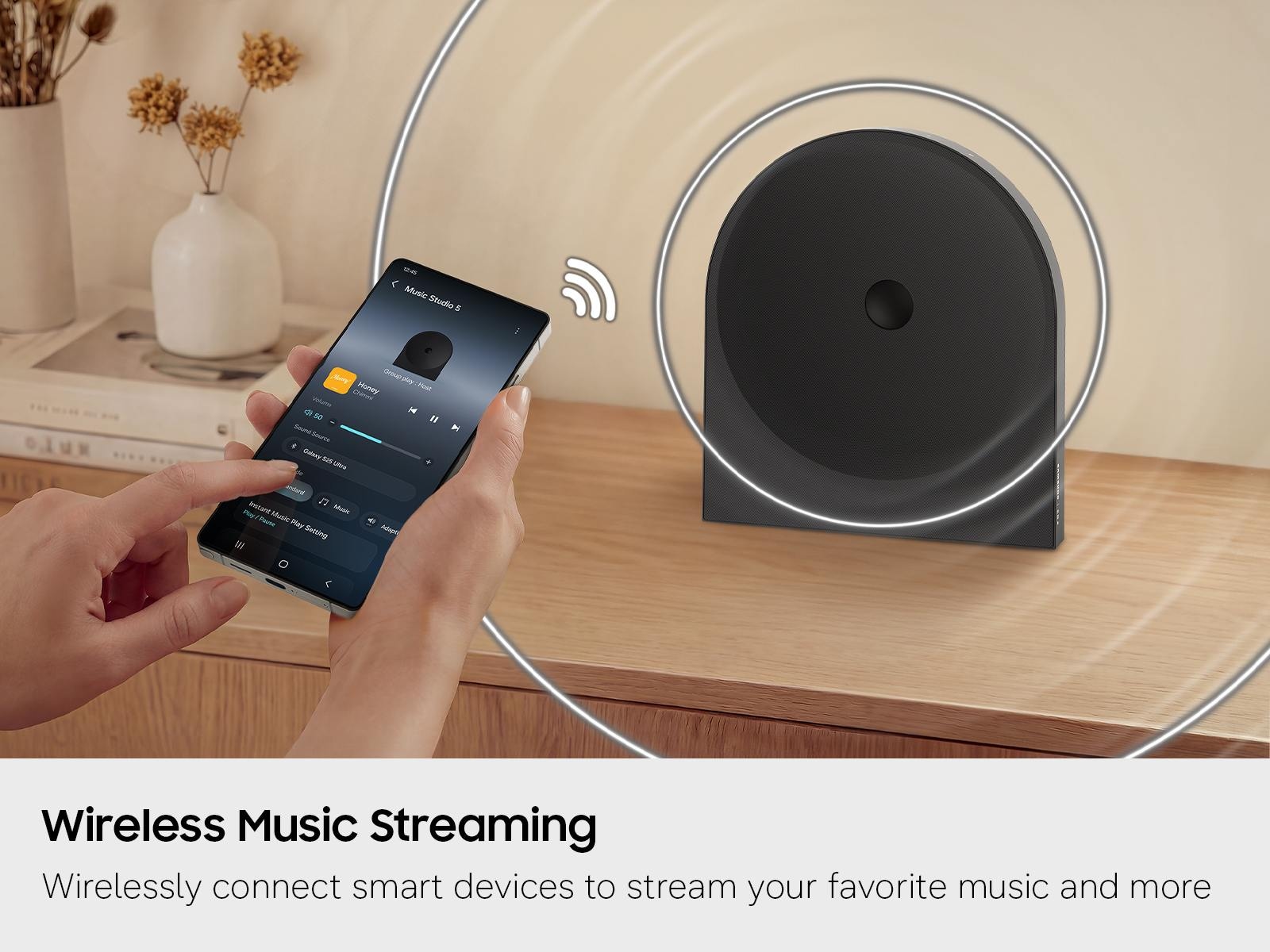 A person using their Samsung smartphone to wirelessly stream music to the Samsung Music Studio LS50H.