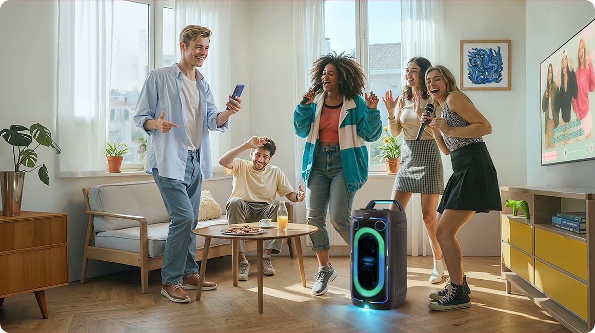 Amigos bailando en un living con la torre de sonido