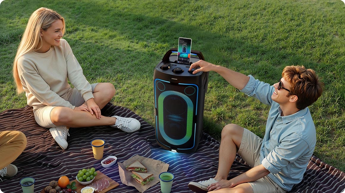 Amigos de picnic en el pasto con la torre de sonido