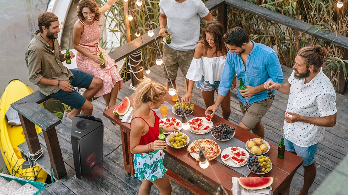 Amigos comiendo al aire libre con la torre de sonido