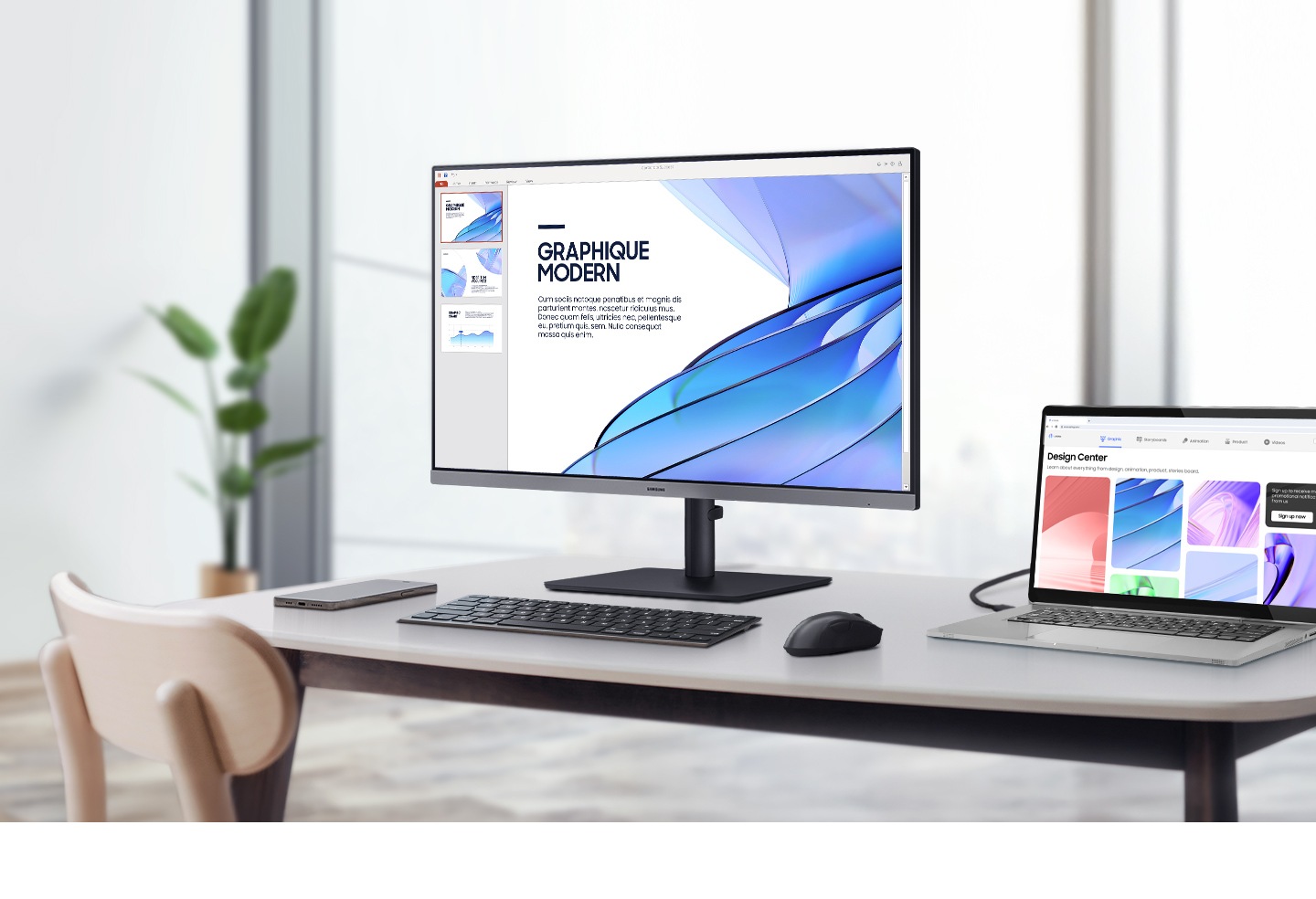 A monitor setup and laptop in an office. The monitor screen shows a PPT slide, while the laptop screen shows various designs.