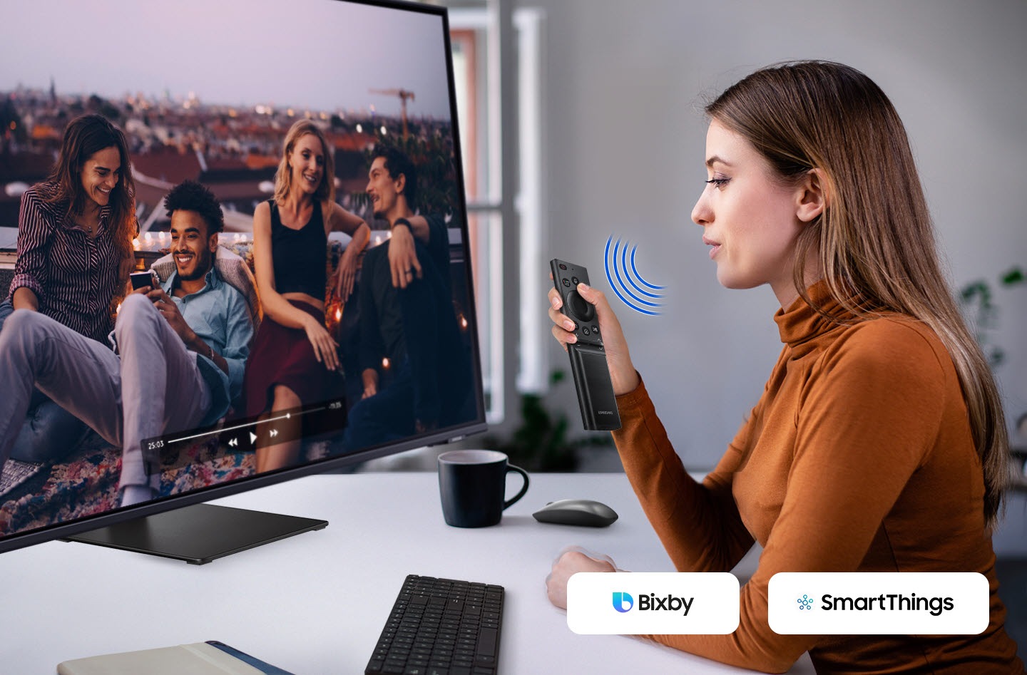 A woman speaks to the monitor. And a video is played on it. The Bixby and SmartThings icon is in the right corner.