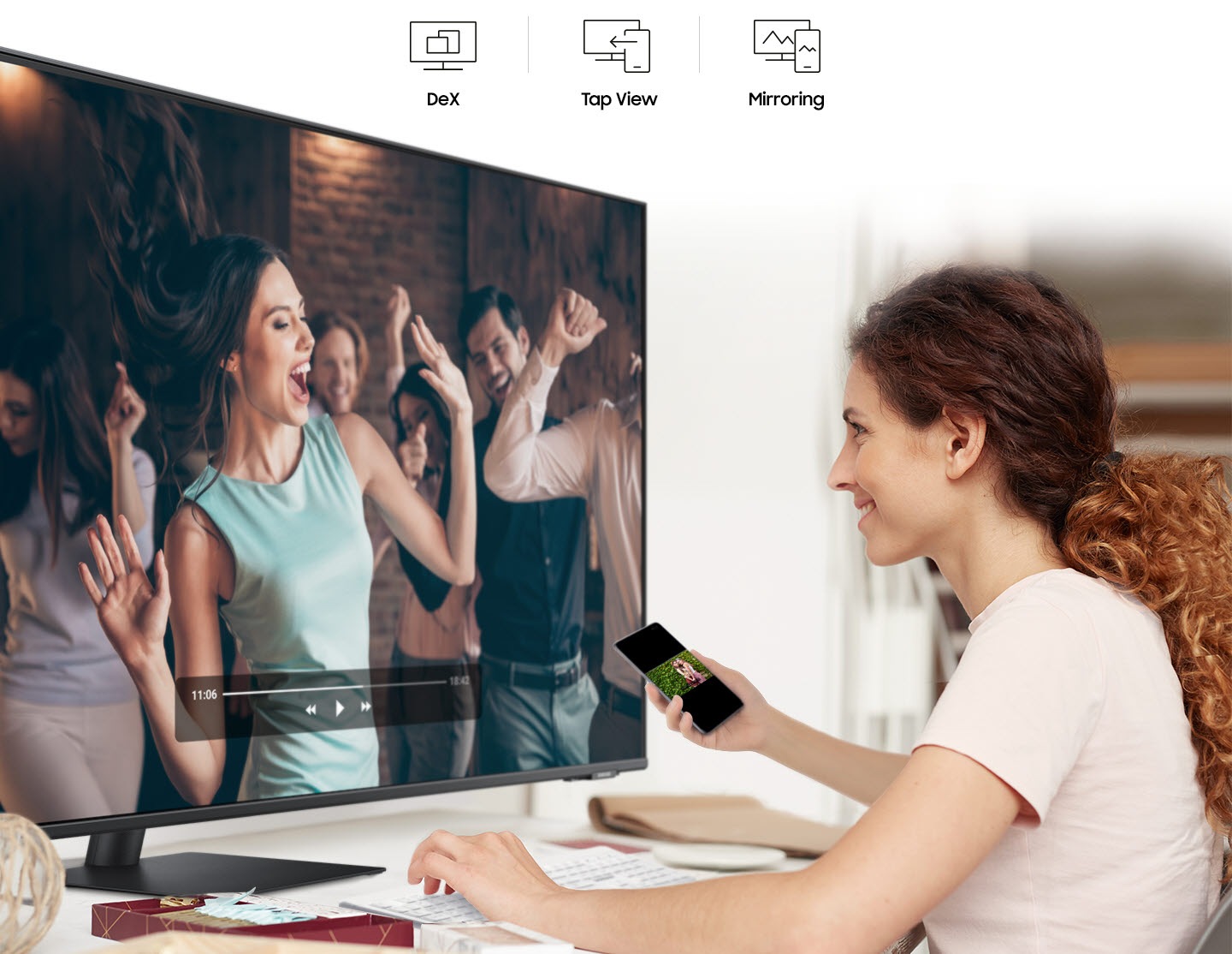 A smiling woman mirrors videos from her phone to her monitor. At the top are the DeX, Tap View, and Mirroring icons.