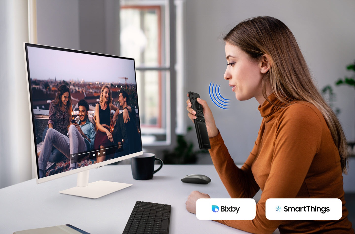 A woman speaks to the monitor. And a video is played on it. The Bixby and SmartThings icon is in the right corner.