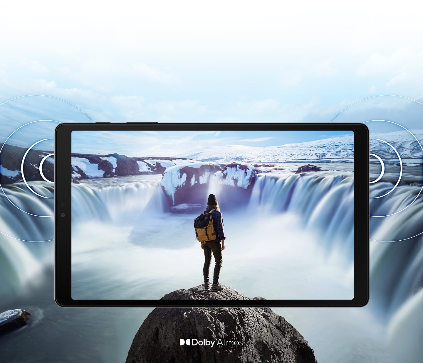 Galaxy A7 Lite seen from the front with an image of a person standing on a rock in front of steaming waterfalls on either side onscreen. The image expands past the edges of the tablet to show the expansiveness of the display. Rings come out from the sides to demonstrate the location of the dual speakers and the immersive sound of Dolby Atmos.