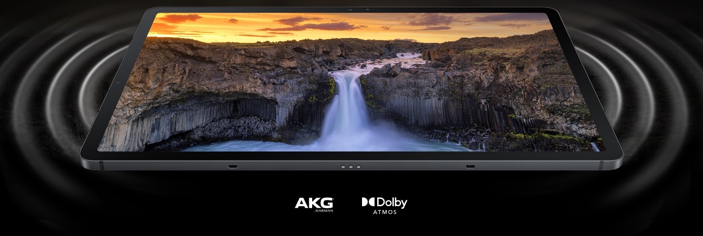 Galaxy Tab S7 FE với màn hình hiển thị phong cảnh sống động. Ở hai bên của máy tính bảng là các vòng tròn thể hiện sóng âm phát ra từ loa kép và thể hiện sự mạnh mẽ của âm thanh. Logo AKG và logo Dolby Atmos.