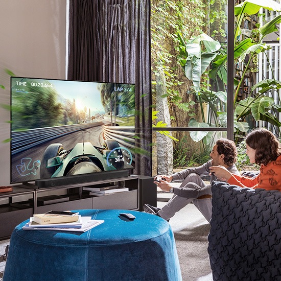 Two friends are enjoying an immersive gaming experience with Samsung Soundbar Game Mode Pro.