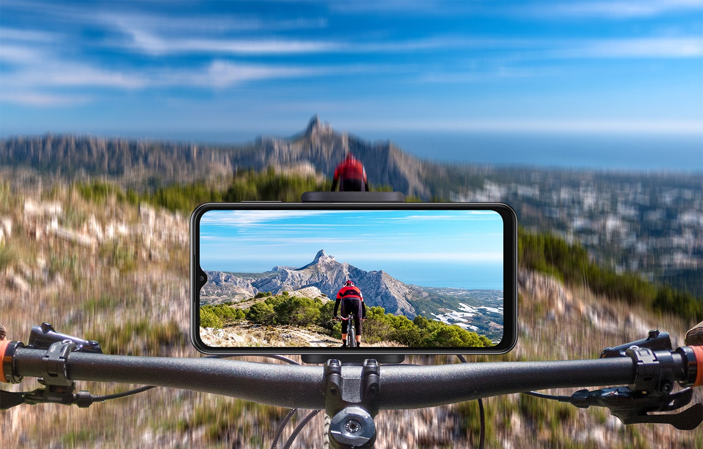 Galaxy A23 được gắn ở chế độ ngang trên ghi đông xe đạp. Ở phía trước, một địa hình đồi núi mờ ảo được hiển thị và trên màn hình, hình ảnh rõ ràng về địa hình cũng như người lái phía trước sẽ được chụp.