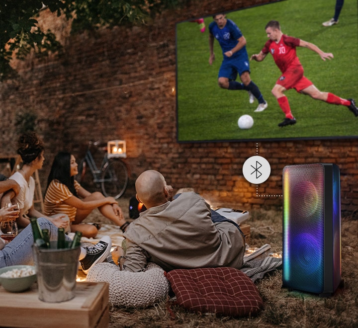 People are watching a soccer game with Sound Tower connected to the TV via Bluetooth.