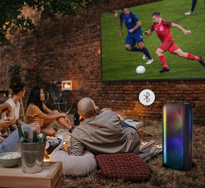 People are watching a soccer game with Sound Tower connected to the TV via Bluetooth.