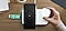 Bộ sạc đôi không dây 15W được kết nối với nguồn điện được đặt trên bàn gỗ. Galaxy S22 + màu đen với dòng chữ 100% trên màn hình nằm ở phía bên trái của thiết bị. Một tay đang cầm một chiếc ốp lưng Galaxy Buds2 màu trắng để đặt nó vào phía bên phải của bộ sạc.