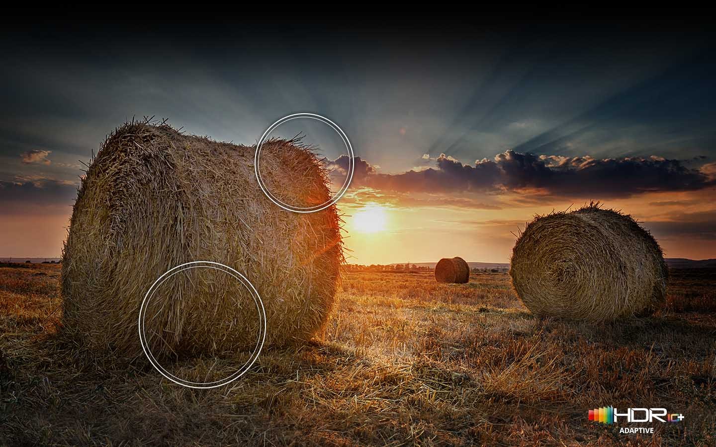 The sun is setting over a wide field with emphasis on a large hay stack. The scene after applying HDR 10+ ADAPTIVE/GAMING technology is much brighter and crisper than the SDR version.