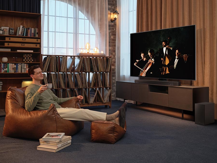 A man enjoys an immersive symphony concert with Dolby Atmos Music in his living room.