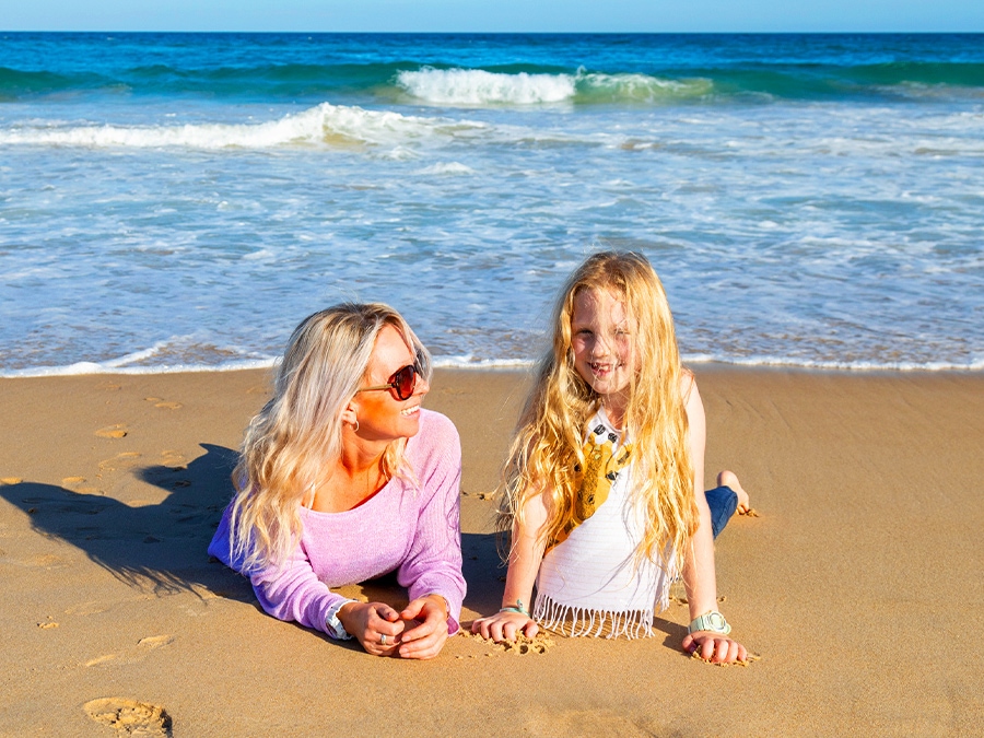 As the scroll is moved from left to right to apply GIF Remaster, a shot of a woman and a young girl lying on a sandy beach  becomes clearer and brighter.
