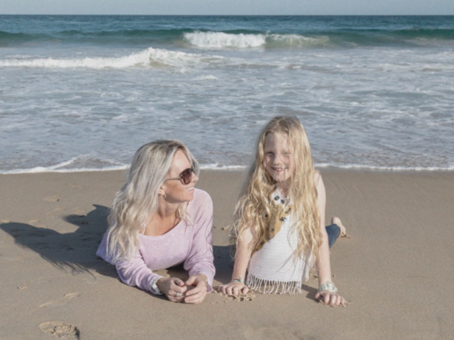 As the scroll is moved from left to right to apply GIF Remaster, a shot of a woman and a young girl lying on a sandy beach  becomes clearer and brighter.