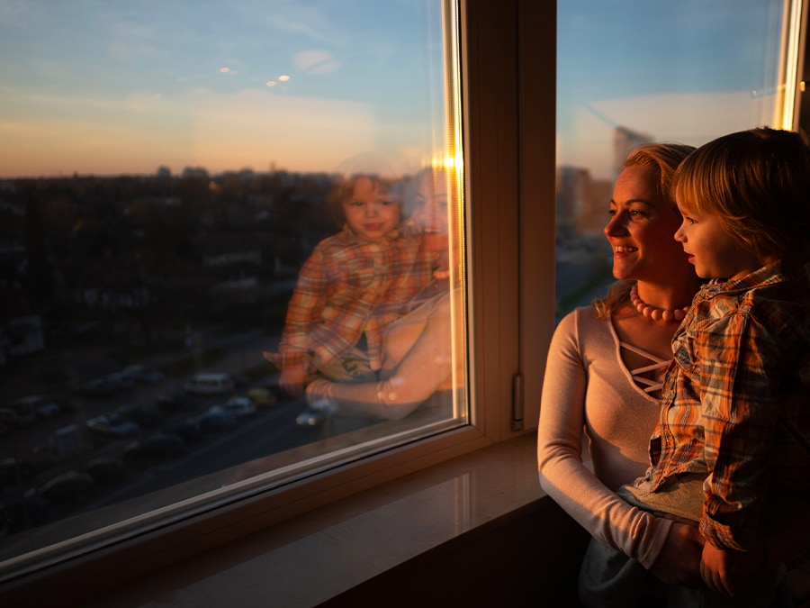 A camera view with the object eraser feature shows a mother and a son looking out the window at sunset. AI Edit is applied and as the scroll moves from left to right, the reflection of the mother and son on the window is removed. 