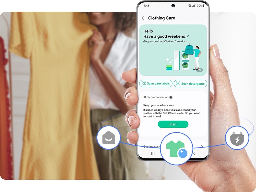Một tay đang cầm điện thoại với tab chăm sóc quần áo đang mở từ ứng dụng SmartThings trên màn hình. Có nhãn chăm sóc quét, quét chất tẩy rửa và làm sạch các tùy chọn máy giặt dựa trên khuyến nghị của AI.