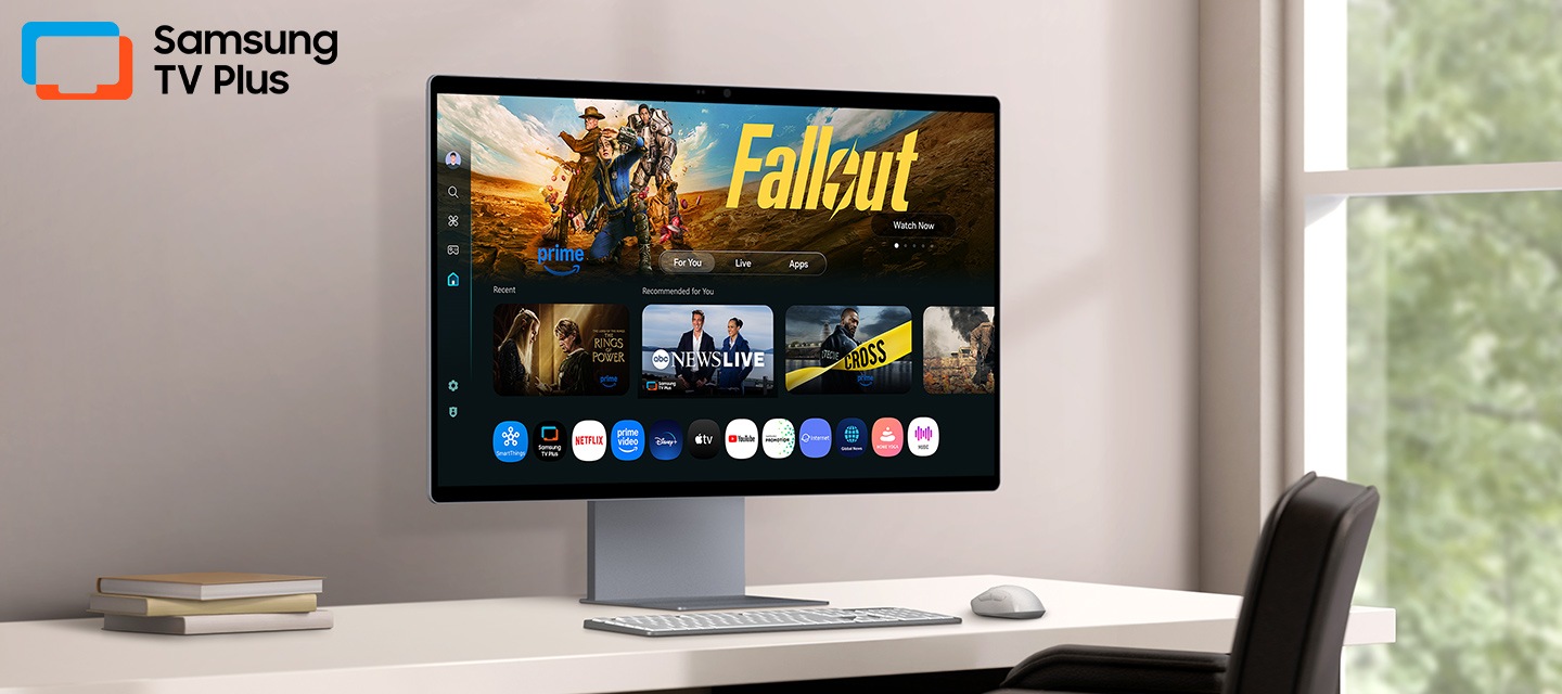 Màn hình trên bàn hiển thị trang Ứng dụng Smart TV với nhiều nội dung và ứng dụng được sắp xếp gọn gàng. Logo Samsung TV Plus.
