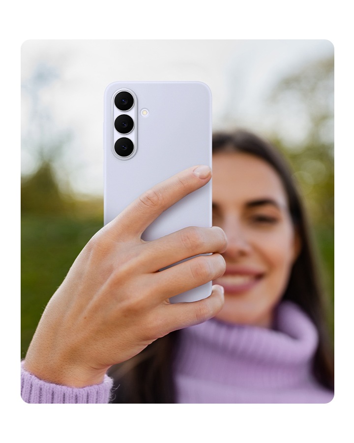 Một người phụ nữ mặc áo len cổ lọ đang cầm chiếc Galaxy S25 FE được bọc trong Ốp lưng Silicone màu Xanh Nhạt.