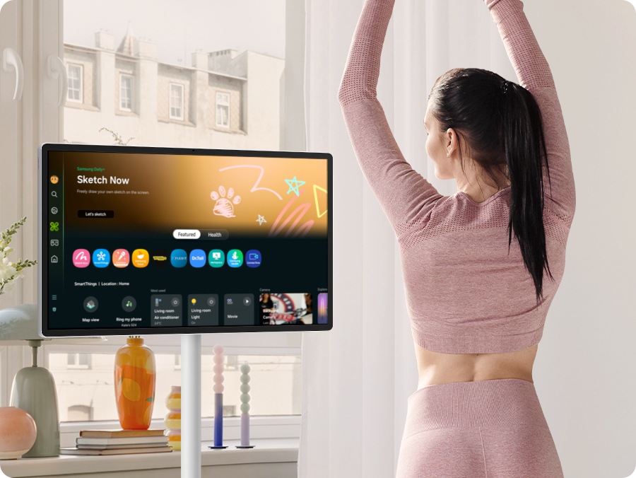 Một phụ nữ thưởng thức Samsung Daily+ trên The Movingstyle. Cuộn xuống màn hình chính để hiển thị các tính năng như SmartThings và trạng thái của các thiết bị nhà thông minh. Tiếp theo, thanh trên cùng được chuyển từ mục Nổi bật sang mục Sức khỏe. Nội dung liên quan đến sức khỏe hiện được hiển thị, với Trình theo dõi tập luyện được ghép nối với Galaxy Watch 6.