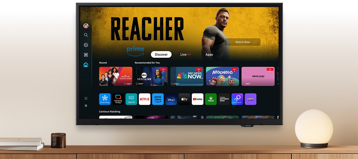 Một chiếc TV Samsung treo tường hiển thị các ứng dụng phổ biến và nội dung được chọn lọc trên màn hình chính One UI Tizen.