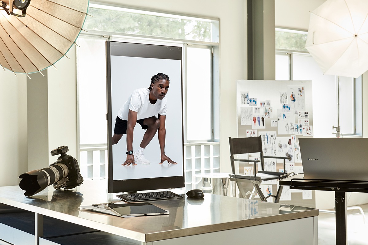 The ViewFinity monitor is on a desk with a camera, and its screen is vertically rotated. A photograph of a woman is on the screen.