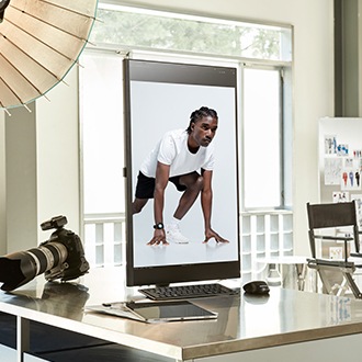 The ViewFinity monitor is on a desk with a camera, and its screen is vertically rotated. A photograph of a woman is on the screen.